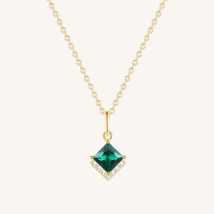 Gold necklace with a green gemstone pendant on a white background