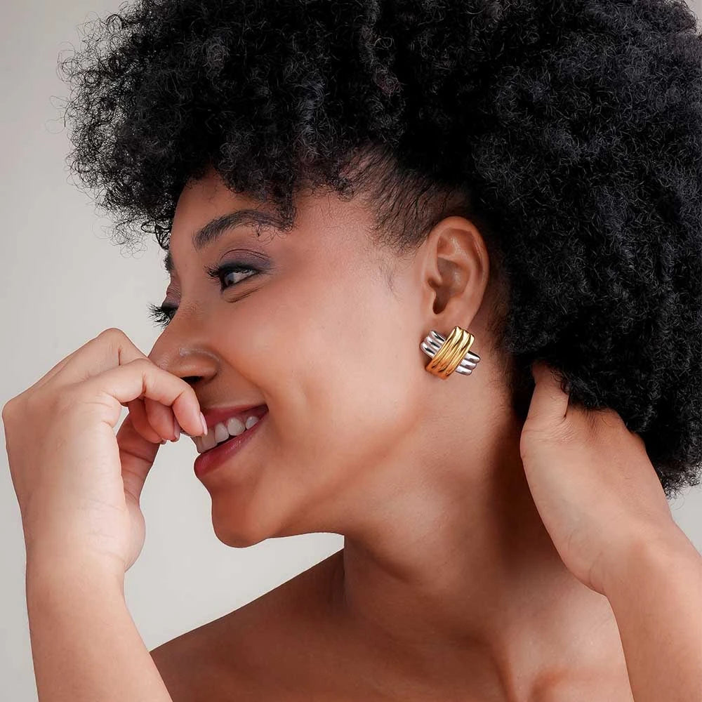 Woman wearing gold earrings with a neutral background