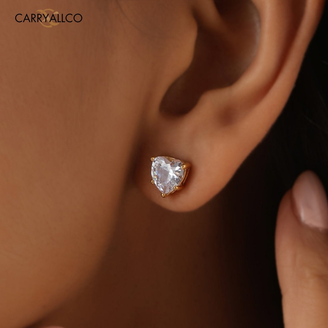 Heart-shaped diamond earring on an ear with 'CARRYALLCO' branding.