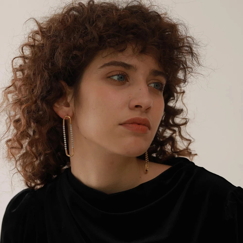 Woman with curly hair wearing gold hoop earrings against a neutral background