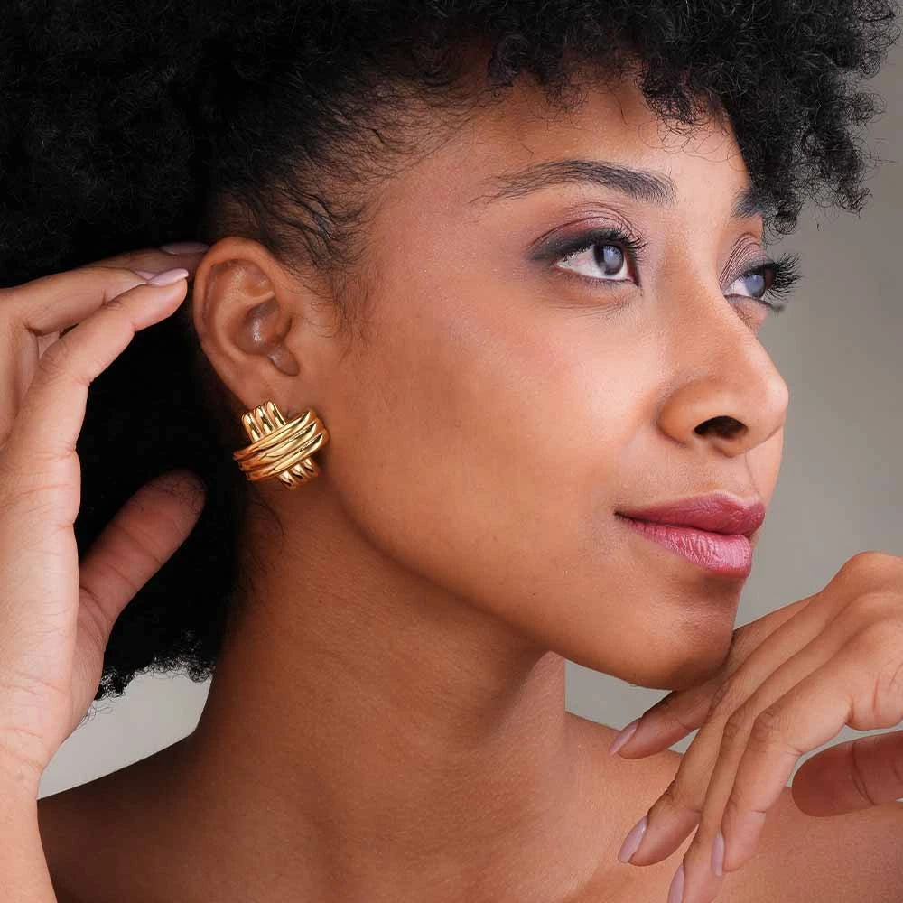 Woman wearing gold earrings with a neutral background