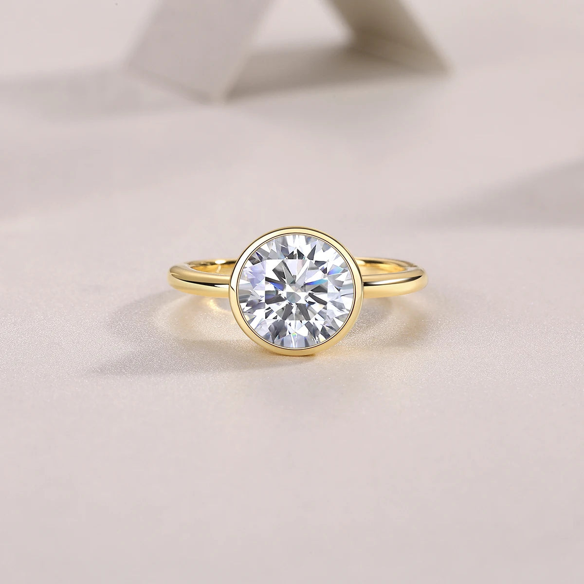 Gold ring with a large diamond on a light beige background
