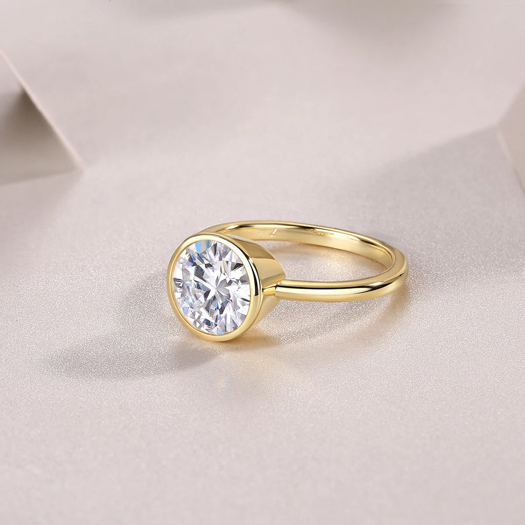 Gold ring with a large diamond on a light fabric background