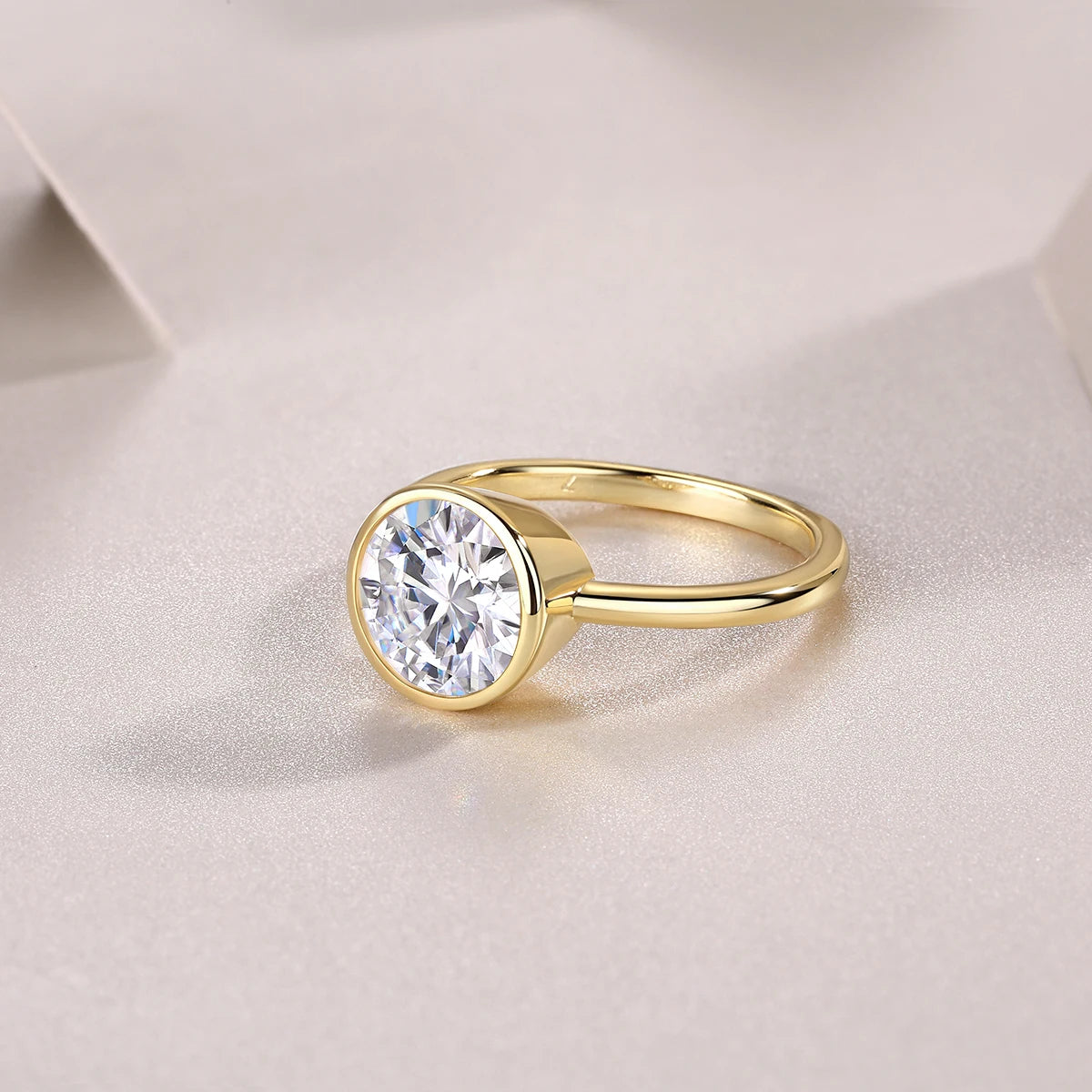 Gold ring with a large diamond on a light fabric background