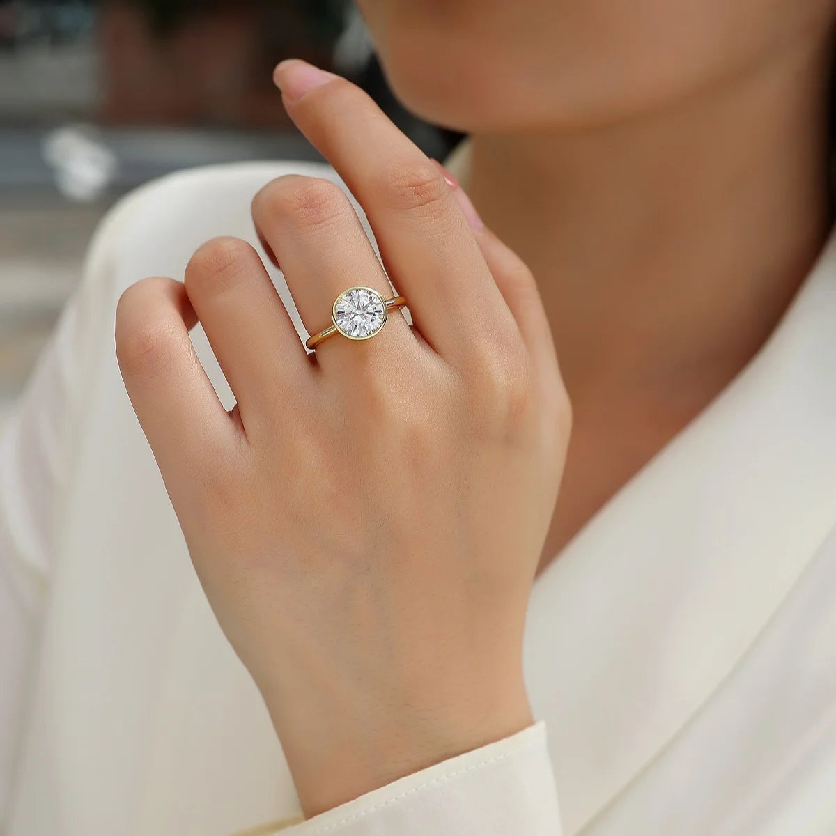 Close-up of a hand wearing a diamond ring with a blurred background