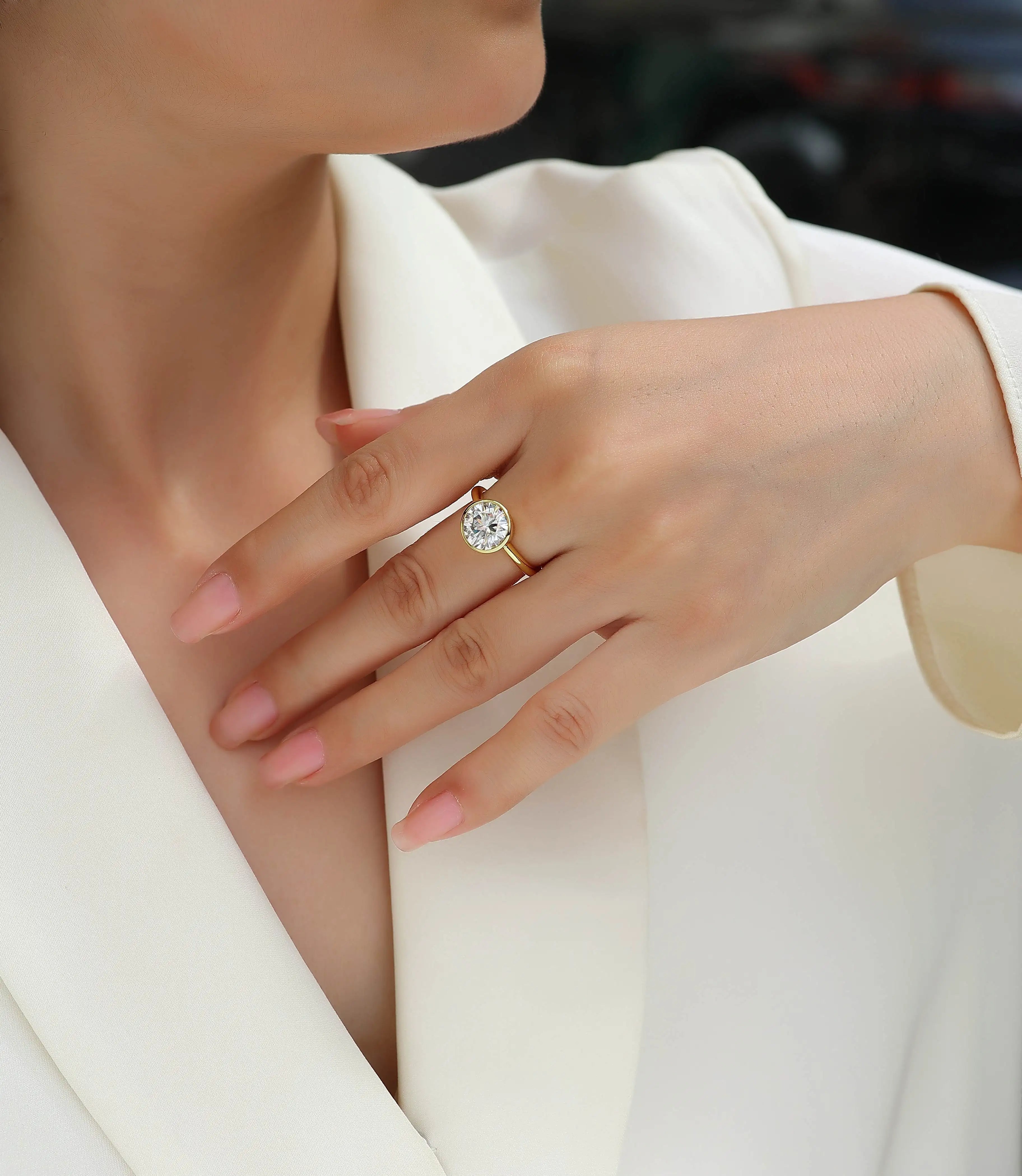 Close-up of a hand wearing a diamond ring with a blurred background