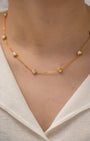 Gold necklace with small diamonds on a person wearing a white top