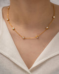 Gold necklace with small diamonds on a person wearing a white top