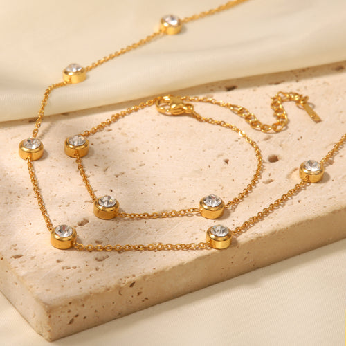 Gold necklace with gemstones on a beige stone surface