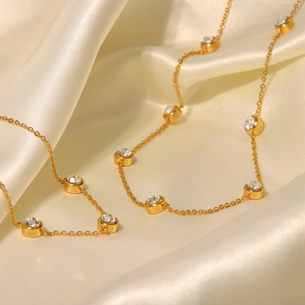 Gold necklace with small crystals on a beige fabric background