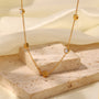 Gold necklace with heart-shaped pendants on a beige stone surface