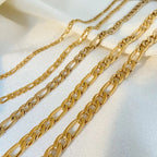 Three gold chain necklaces on a light fabric background