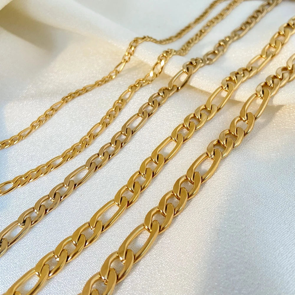 Three gold chain necklaces on a light fabric background