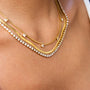 Close-up of layered gold necklaces on a person's neck