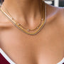 Close-up of a person wearing two gold necklaces with a blurred background