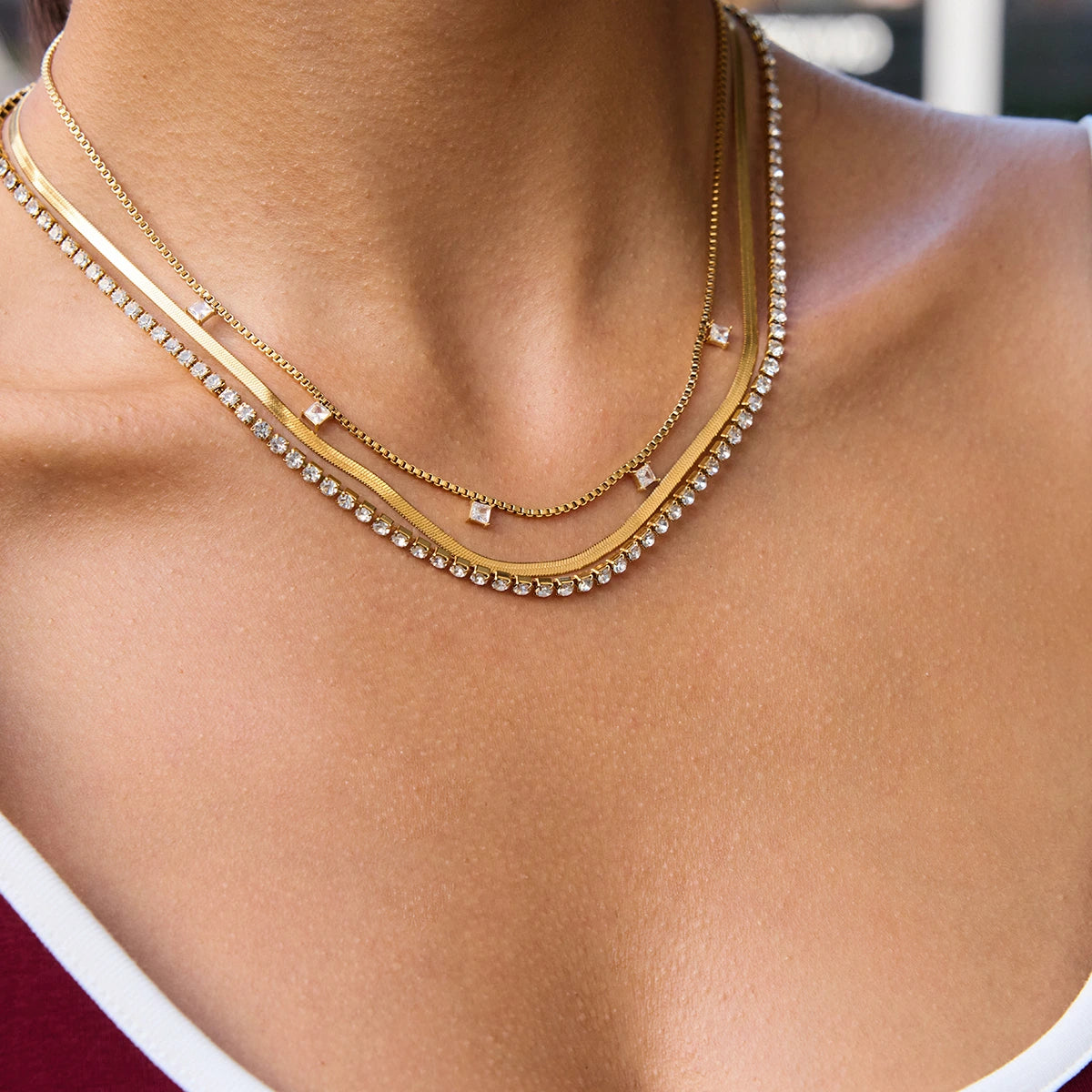 Close-up of a person wearing two gold necklaces with a blurred background