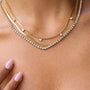Two gold necklaces with diamond accents on a person's neck