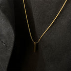 Gold necklace with a small pendant on a black background
