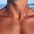 Close-up of a necklace on a person with a blurred beach background