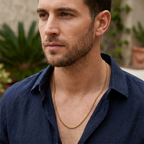Man wearing a gold chain necklace with a blurred outdoor background