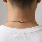 Gold chain necklace on a person wearing a white shirt against a neutral background