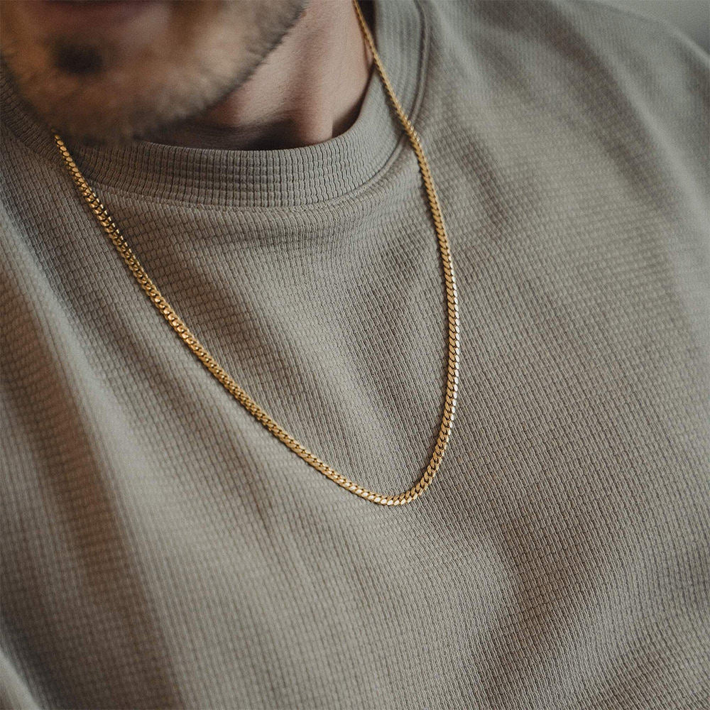 Gold chain necklace on a person wearing a green sweater