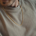 Gold chain necklace on a person wearing a green sweater