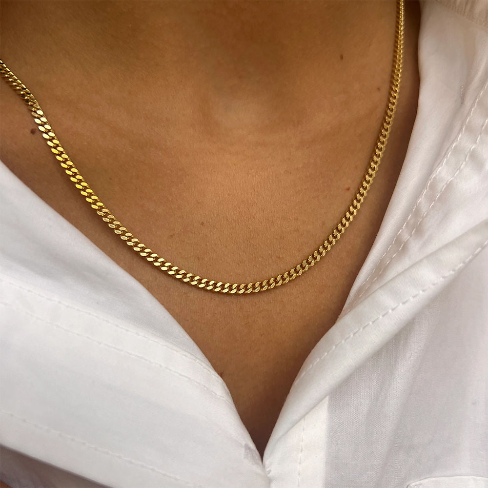 Gold chain necklace worn by a person with a white shirt