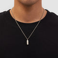 Person wearing a black shirt with a silver necklace featuring a pendant.