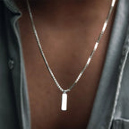 Silver necklace with a rectangular pendant on a blurred background