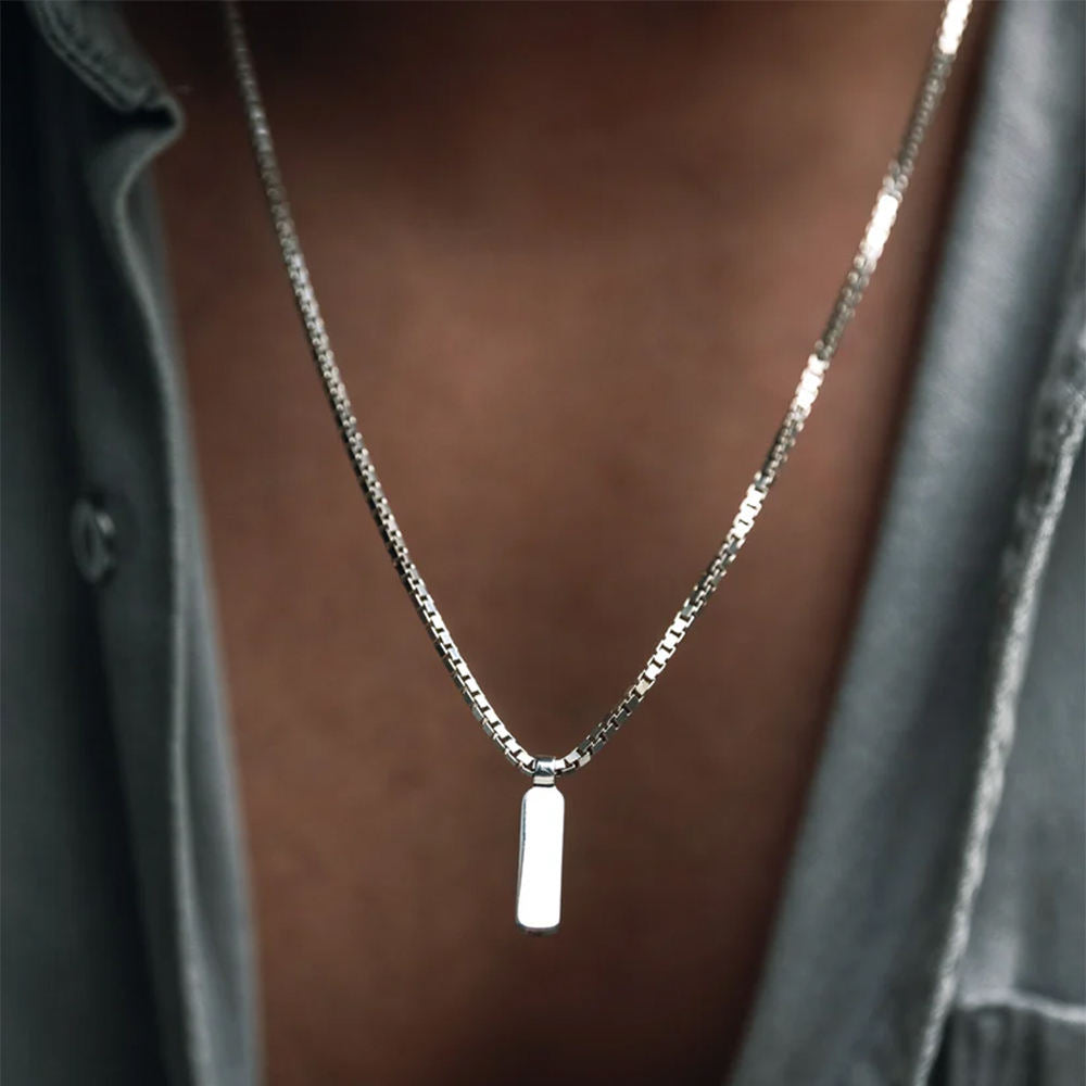 Silver necklace with a rectangular pendant on a blurred background