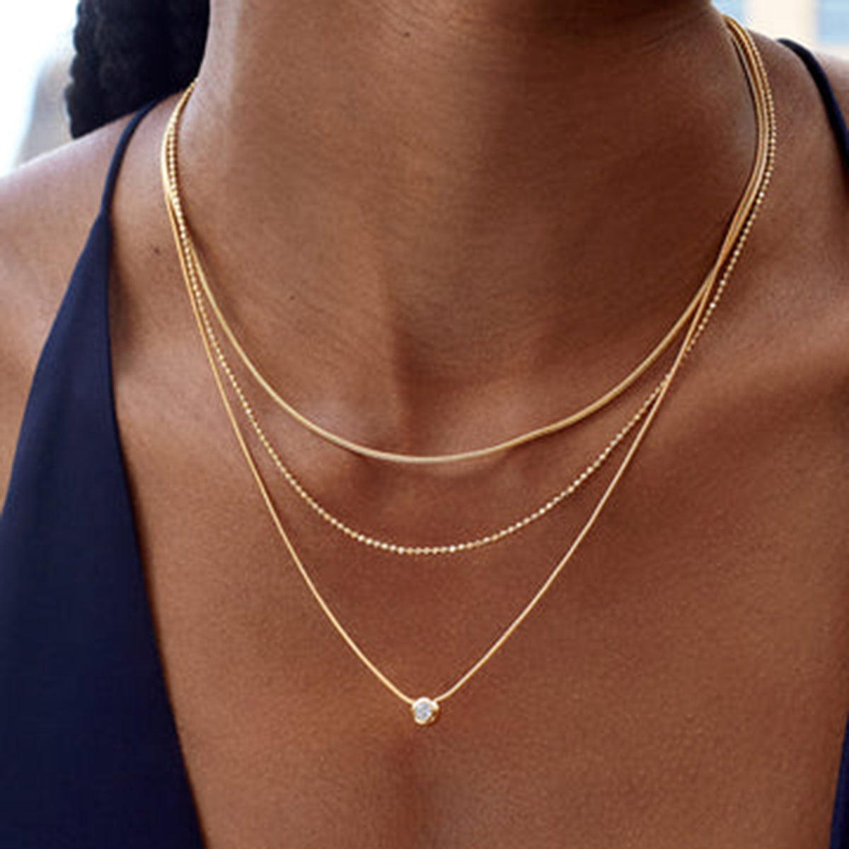 Gold necklaces on a person with a blurred background