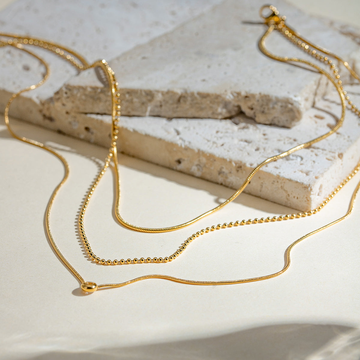 Gold necklace on a textured stone surface