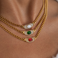 Three gold chains with gemstone pendants on a skin background