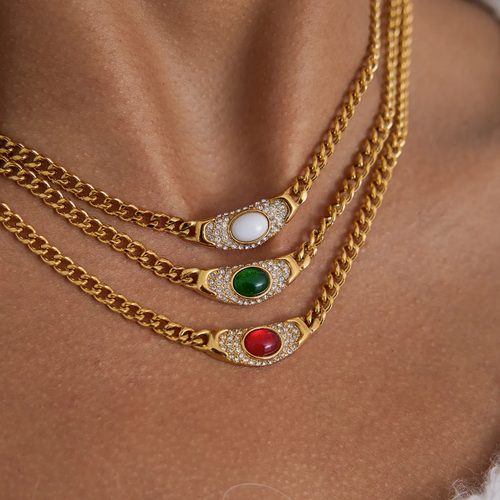 Three gold chains with gemstone pendants on a skin background