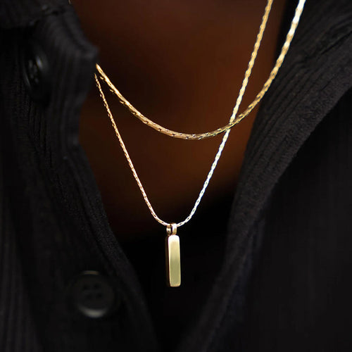 Gold necklace with a pendant on a dark background