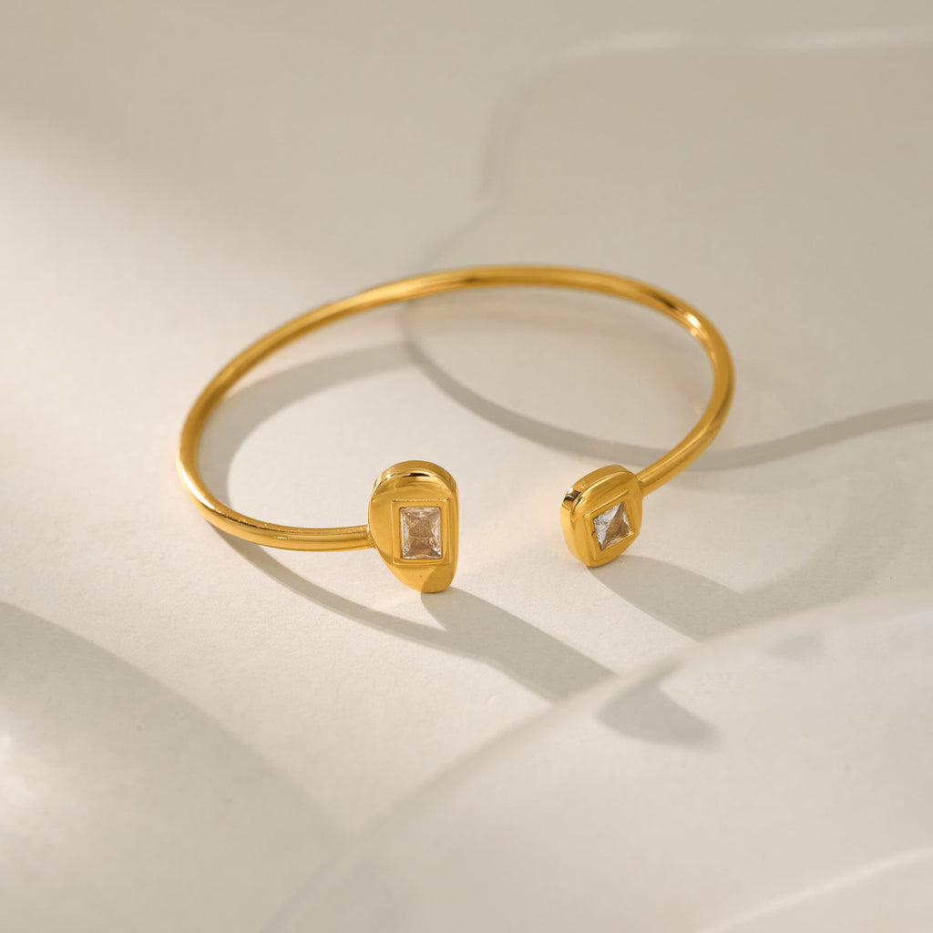 Gold bracelet with diamond-like stones on a light background