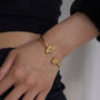 Gold bracelet with a diamond on a wrist against a neutral background