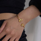 Gold bracelet with a diamond on a wrist against a neutral background