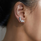 Close-up of an ear wearing a silver earring with three teardrop-shaped gemstones.