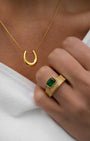 Gold necklace and ring with green gemstone on a white background