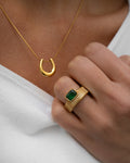 Gold necklace and ring with green gemstone on a white background