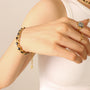 Hand wearing a gold bracelet and ring on a plain background