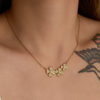 Gold necklace with a clover-shaped pendant on a person's neck.