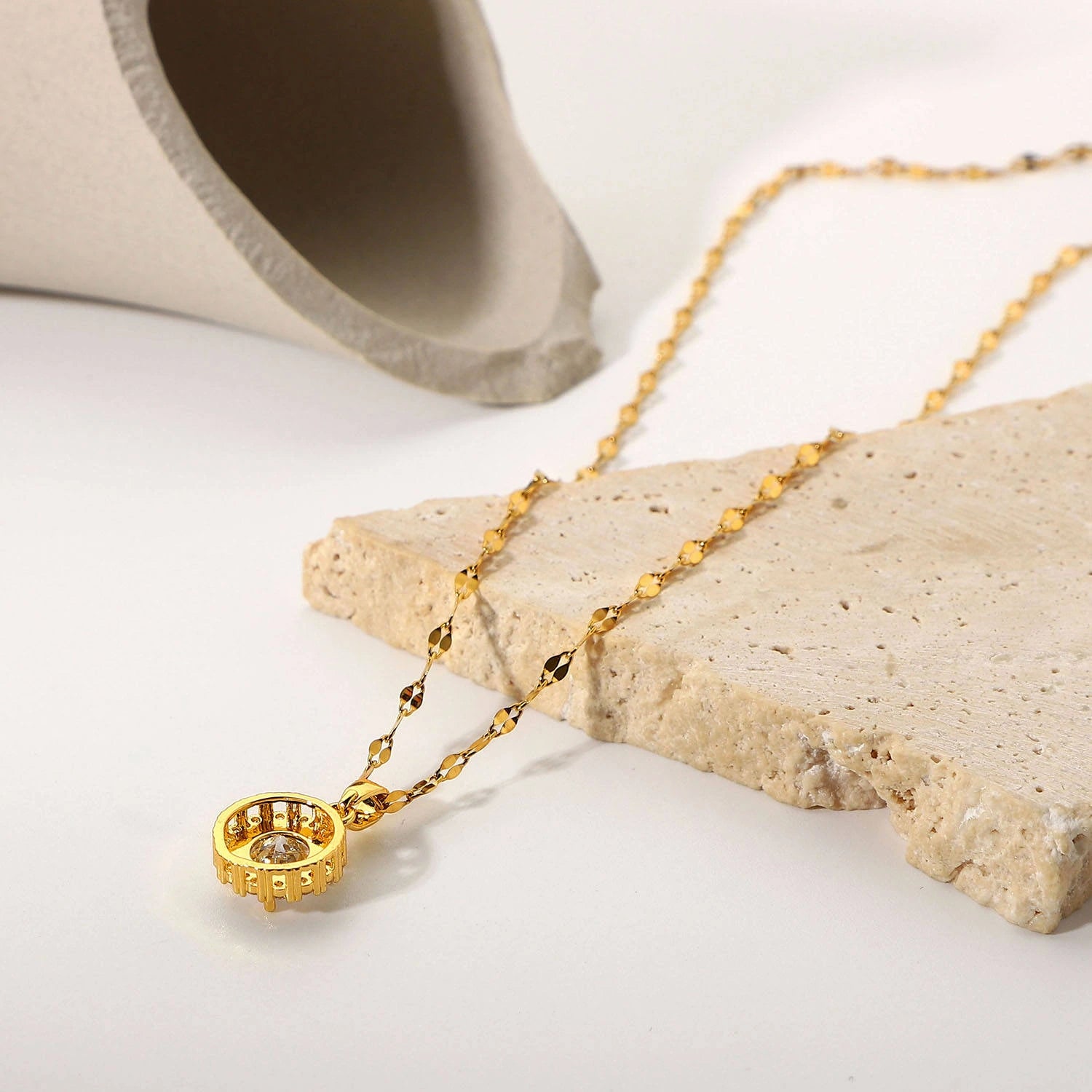 Gold necklace with a pendant on a stone surface