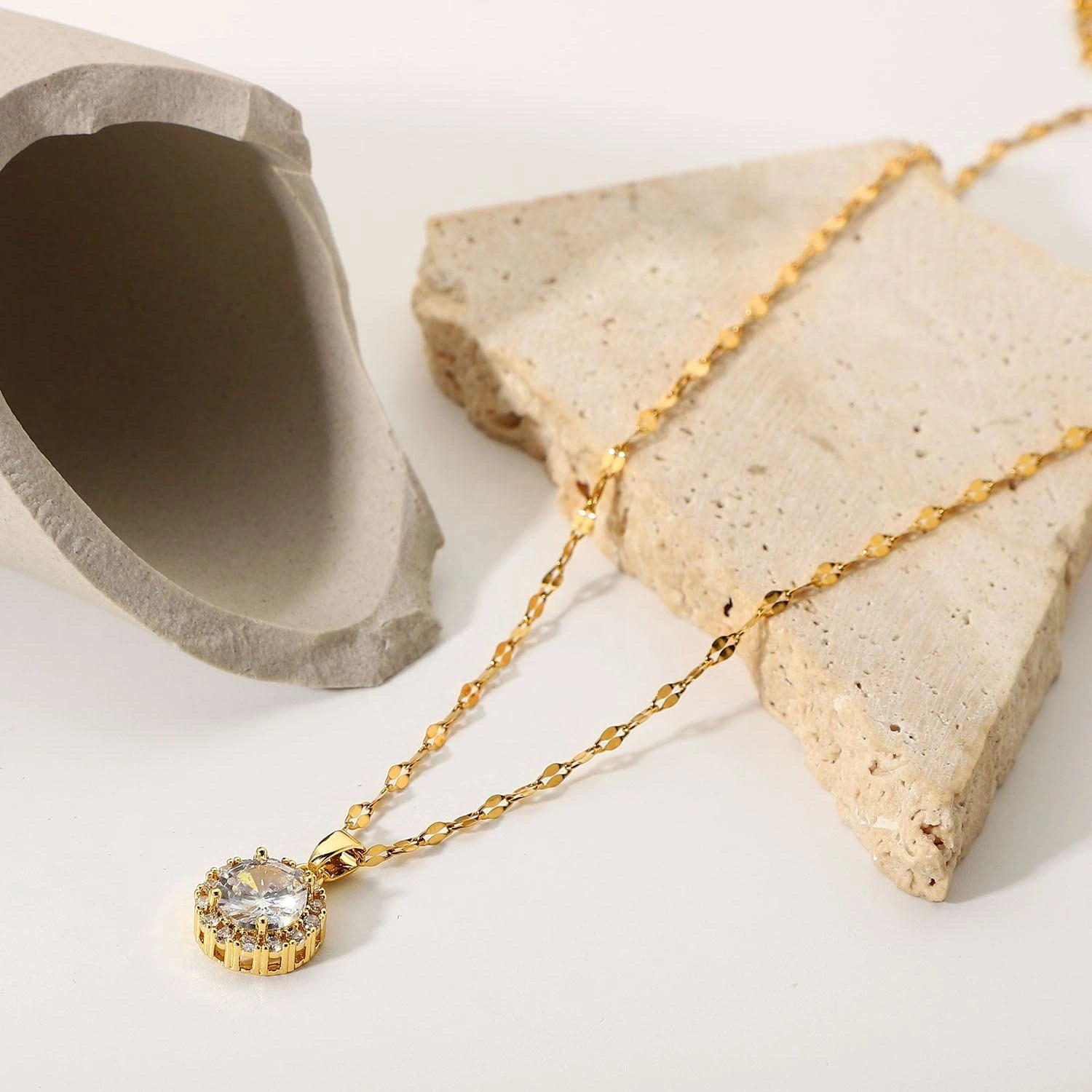 Gold necklace with a diamond pendant on a stone surface