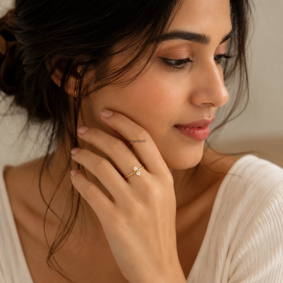 Woman wearing a gold earring and ring, close-up of face and hand.