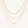 Three gold necklaces on a beige background