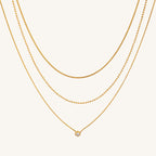 Three gold necklaces on a beige background