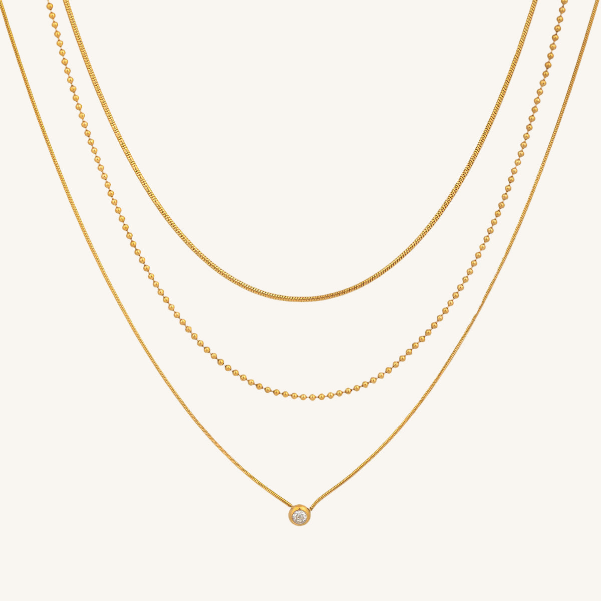 Three gold necklaces on a beige background